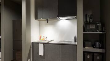 Een kleine keuken met een wasmachine, een magnetron en een koffiezetapparaat.