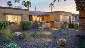 A modern house with a patio, palm trees, and a desert garden.