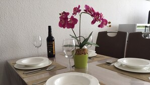 Ein Esstisch, gedeckt mit Tellern, Besteck, einer Weinflasche und einer Topf-Orchidee.