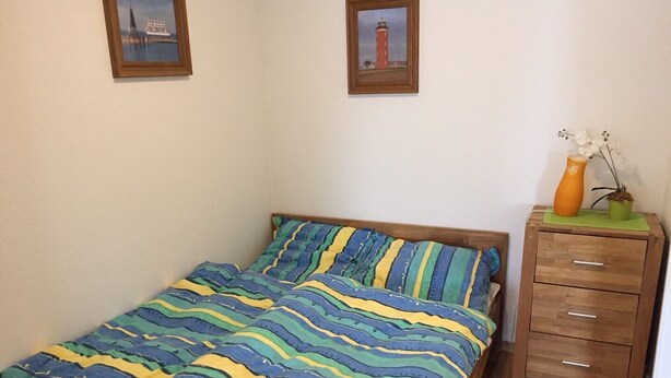 Ein Schlafzimmer mit einem Bett, einem Schminktisch und zwei gerahmten Bildern an der Wand.