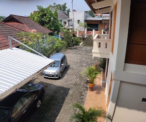 Zona residenziale con vialetto lastricato, auto parcheggiate e case con diversi tipi di tetto.