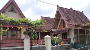 A traditional house with a tiled roof, a stone wall, and a hexagonal tiled pathway. - Omahe Winahyu Homestay (Jogja)