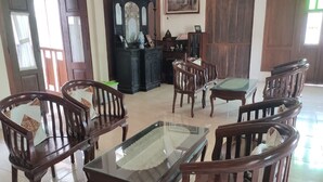 A room with wooden furniture, including chairs and a table, and a dark wooden cabinet with a mirror. - Omahe Winahyu Homestay (Jogja)