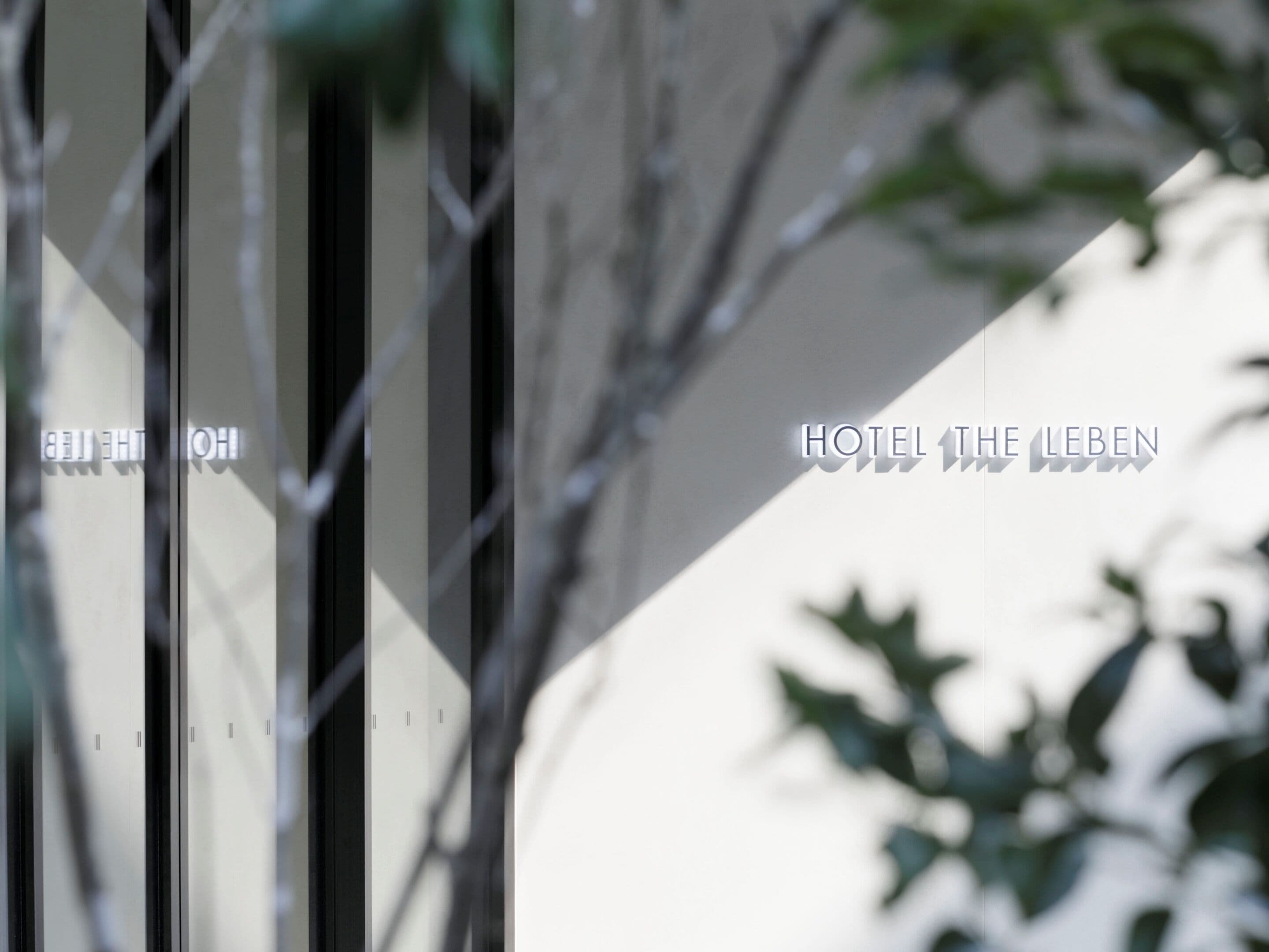 A modern building facade with vertical lines and a sign reading "HOTEL THE LEBEN".