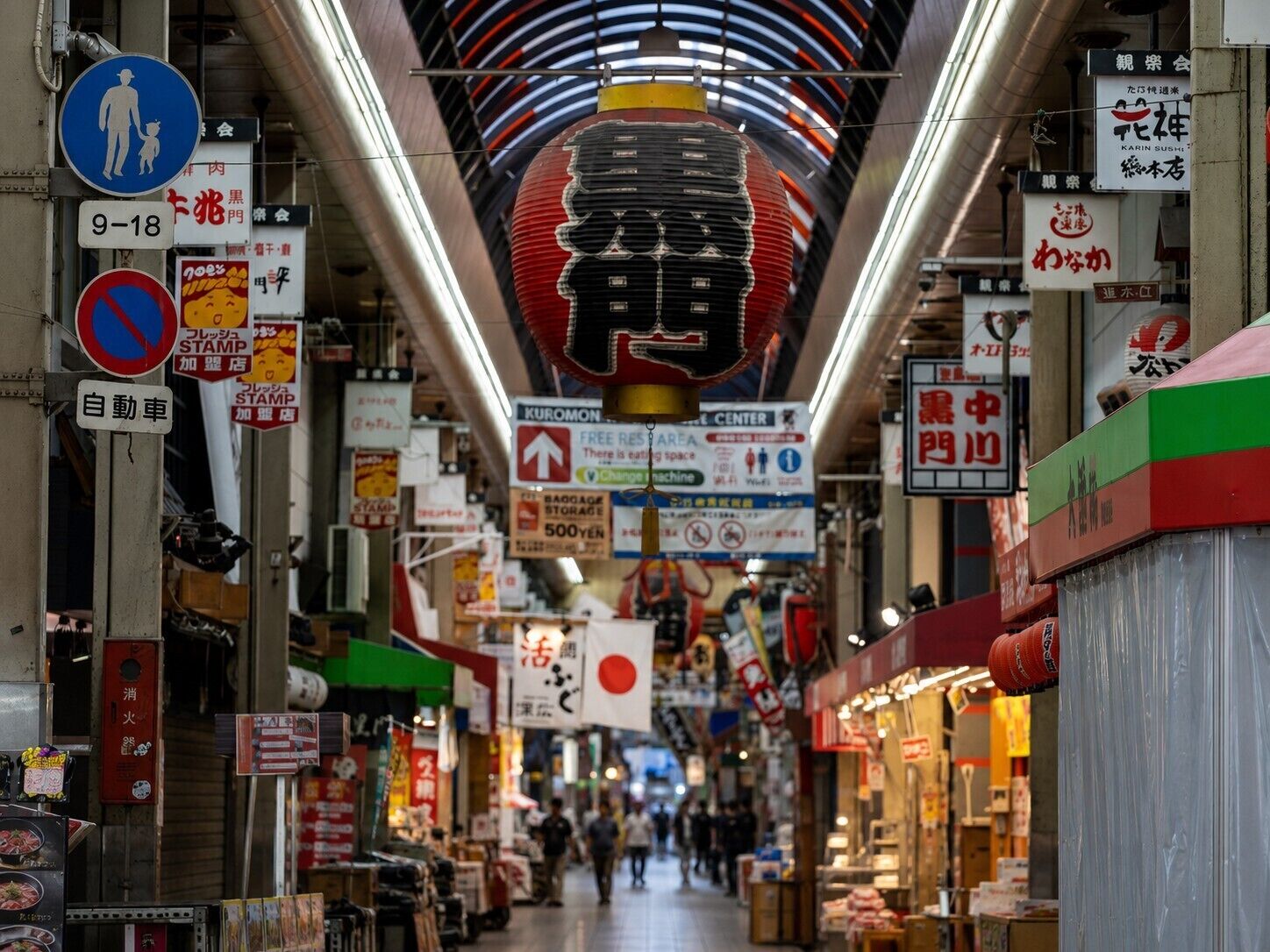 A bustling indoor market with various signs and stalls.