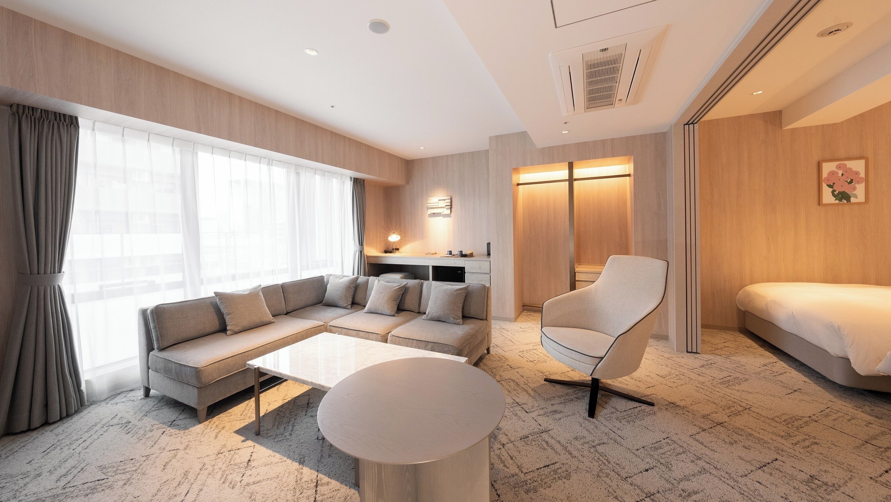 Una habitación de hotel moderna con sofá, sillón, cama y zona de escritorio.