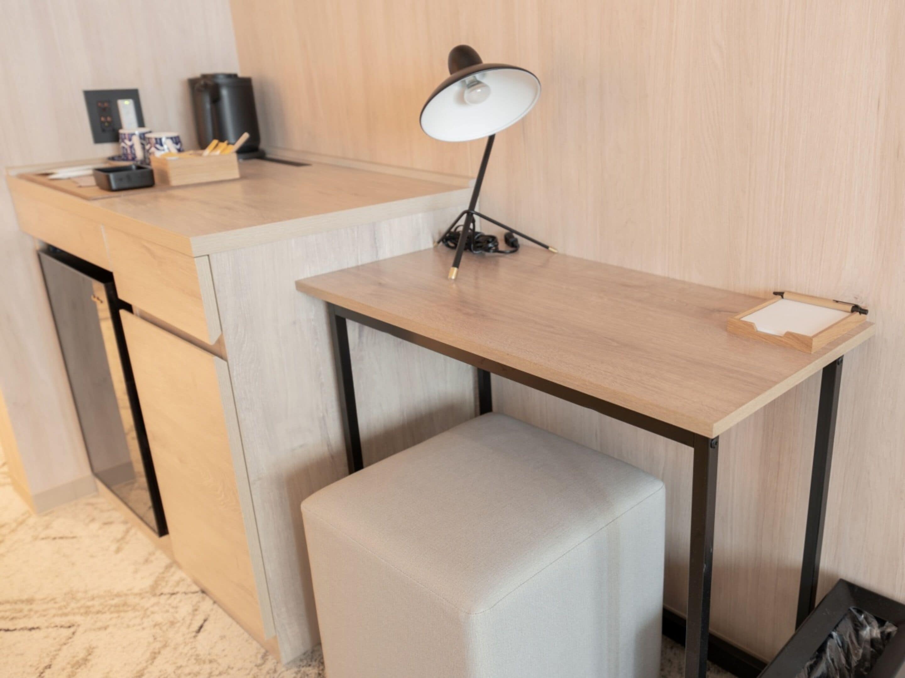 Un espace de travail compact comprenant un bureau, une chaise, une lampe et une machine à café.