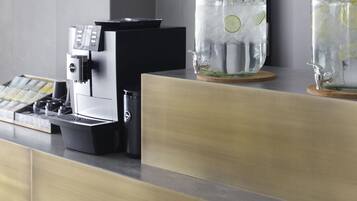 Eine Kaffeemaschine, ein Wasserspender und zwei Gläser mit Limettenscheiben auf einer Arbeitsplatte.