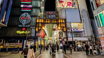 A busy urban street at night with illuminated signs and storefronts.
