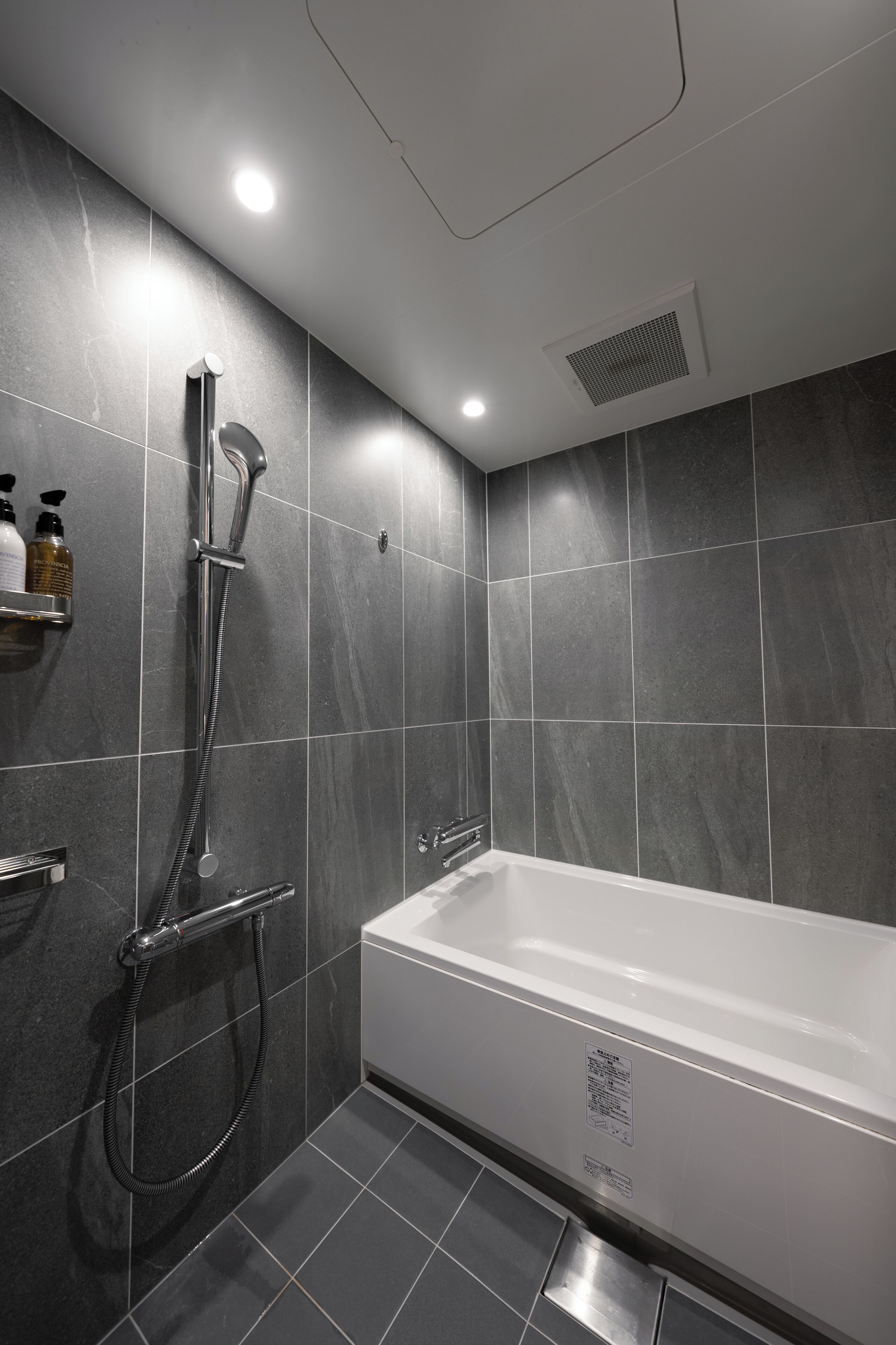 A modern bathroom with a bathtub, shower, and tiled walls.