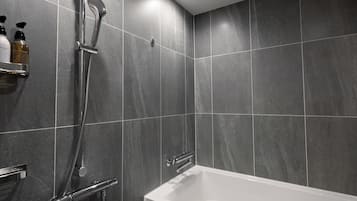 A modern bathroom with a bathtub, shower, and tiled walls.