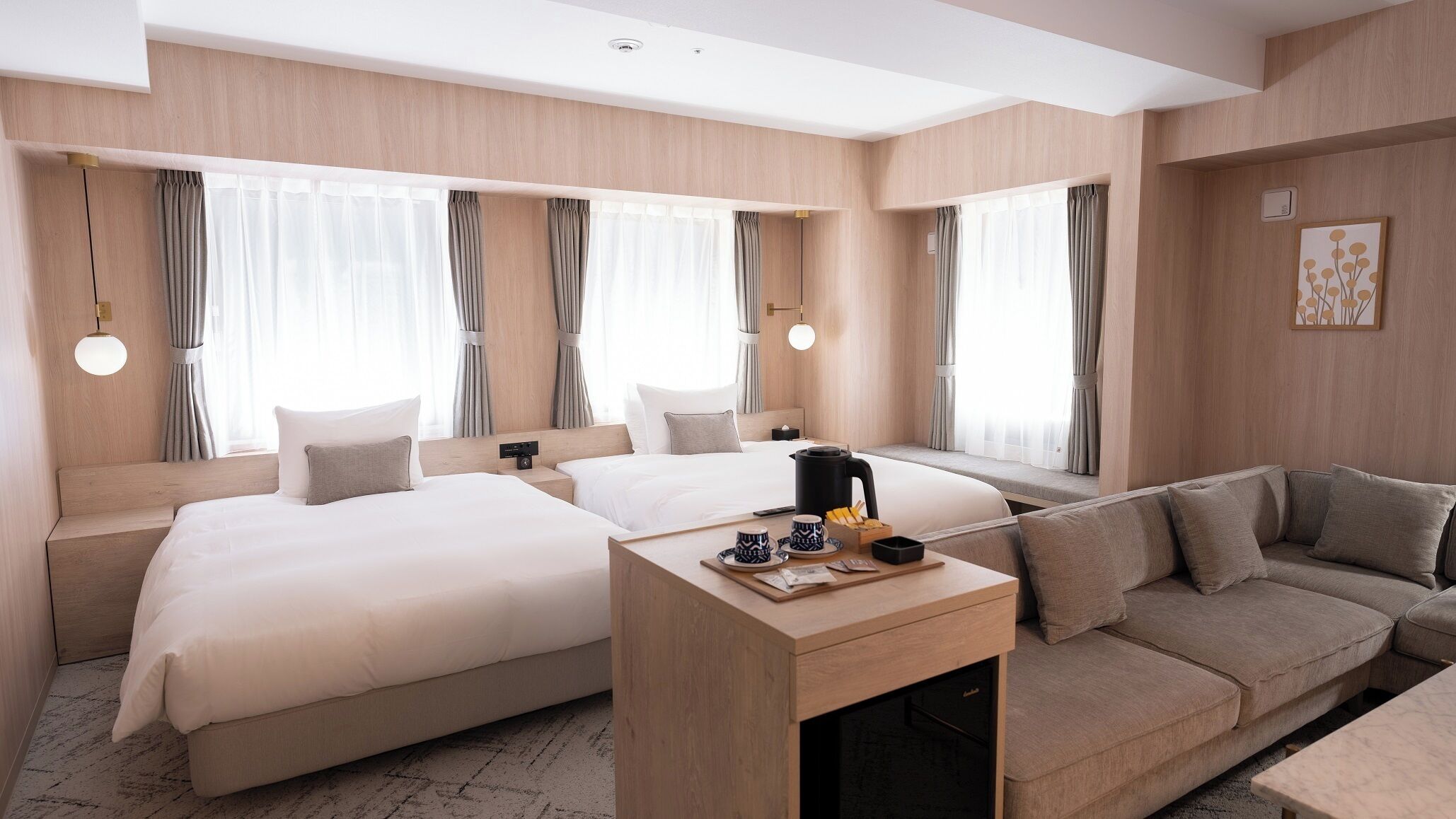 Habitación de hotel con dos camas, un sofá, una mesa de centro y vista a la ciudad.