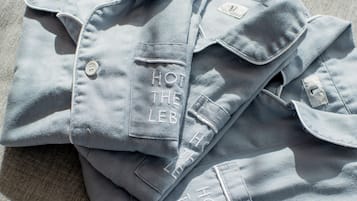 A neatly folded light blue shirt with embroidered text on the pocket.
