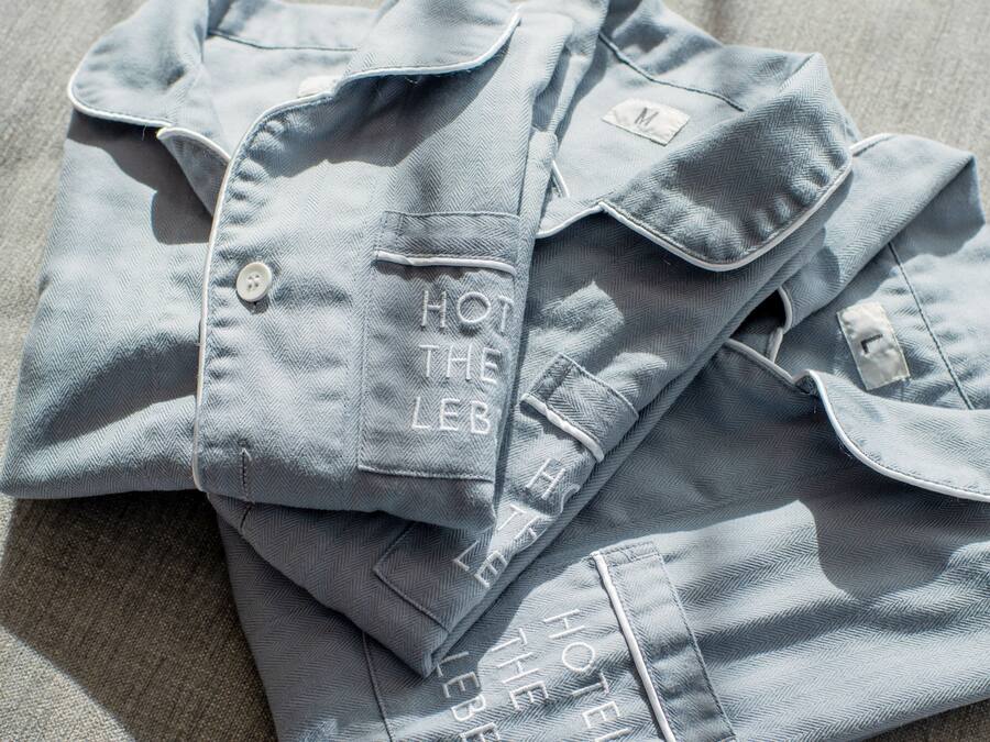 A neatly folded light blue shirt with embroidered text on the pocket.