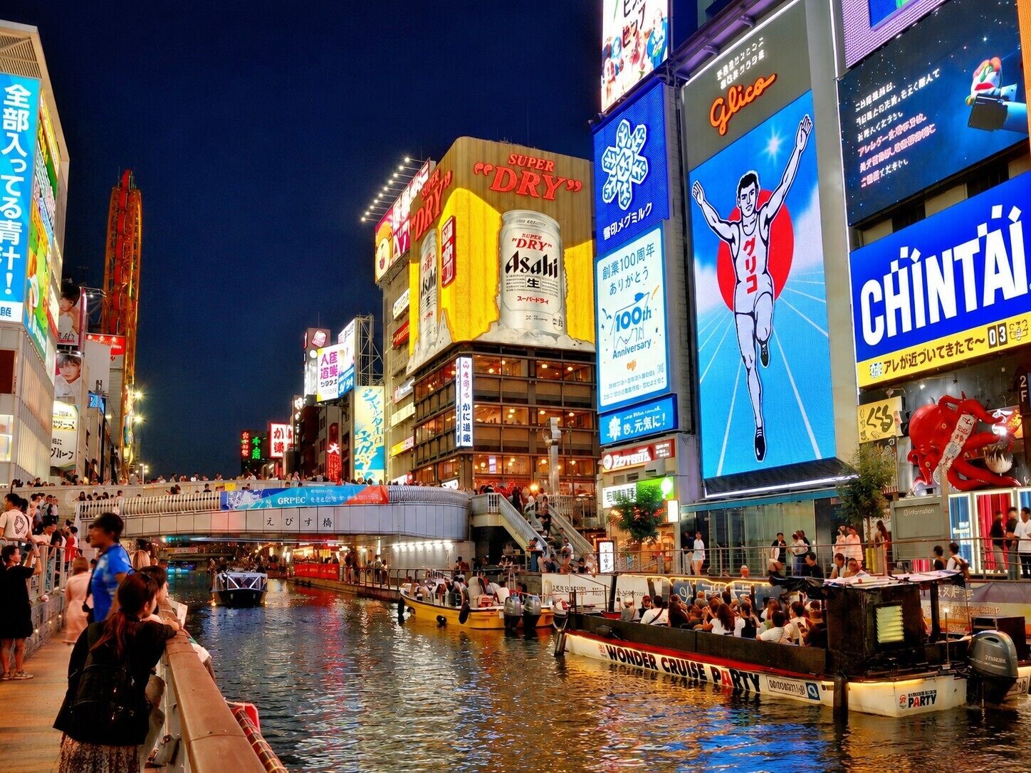 A bustling urban waterfront with boats and people.
