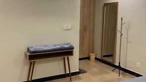 Ein modernes Schlafzimmer mit Bett, Sitzbank, Klimaanlage, Spiegel und Tür.