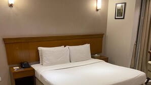 Ein großes Bett mit hölzernem Kopfteil, zwei Nachttische und ein Telefon auf der linken Seite.