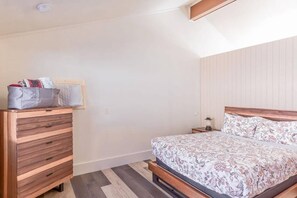 Ein Schlafzimmer mit einem Holzkapitänsbett, einer Bettdecke mit floralem Muster und einem Nachttisch mit Lampe.