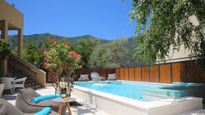Uma área de piscina com hidromassagem, espreguiçadeiras e uma cascata.