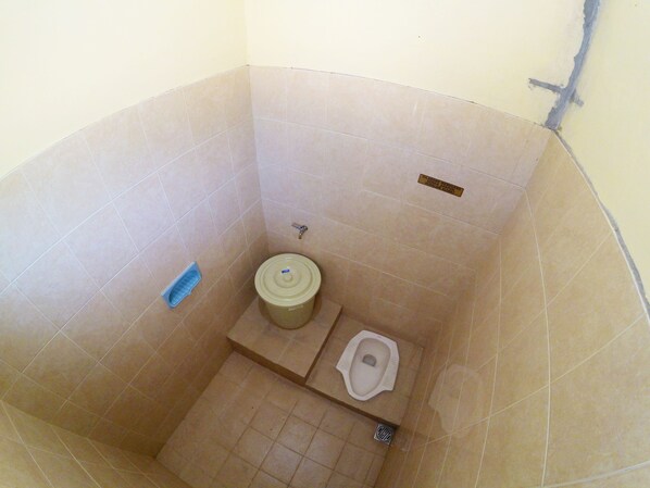 A small, tiled bathroom with a toilet, bidet, and a trash bin.