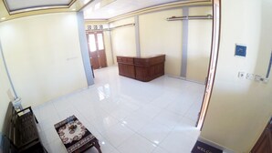 A spacious lobby with a reception desk, a small table with a floral tablecloth, and a welcome mat. - Next Trip Homestay Jogja (Jogja)