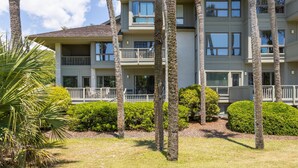 A multi-story hotel with balconies, palm trees, and well-maintained lawns. - Kiawah Exclusives | 4973 Turtle Point Villa (Kiawah Island)