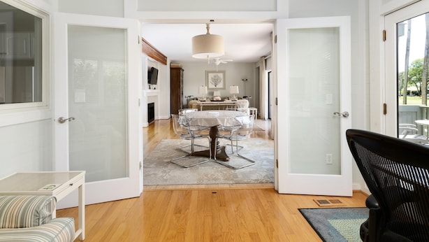 A modern interior with a dining area, a sofa, and a chair. - Kiawah Exclusives | 4973 Turtle Point Villa (Kiawah Island)