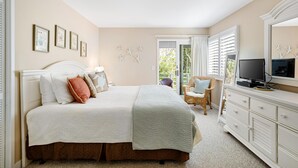 Un dormitorio con cama, cómoda, televisor y una silla.
