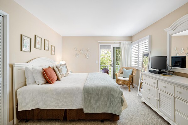 Un dormitorio con cama, cómoda, televisor y una silla.