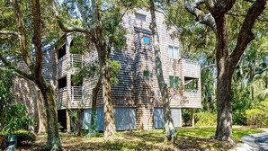 Un edificio moderno con una fachada de madera distintiva, rodeado de árboles maduros.