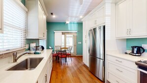 Una cocina moderna con armarios blancos, un refrigerador de acero inoxidable y una mesa de comedor de madera con sillas.
