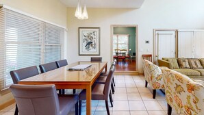 Un comedor con una mesa y sillas de madera, un sofá con tapicería floral y una obra de arte enmarcada en la pared.