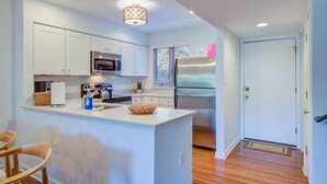 A modern kitchen with white cabinetry, stainless steel appliances, and a central island.