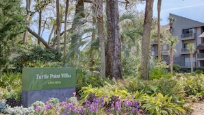 Skilt for Turtle Point Villas i en naturlig have.