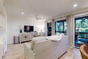 Relax in this cozy living space with a large TV, comfortable sofa, and a wicker chair.