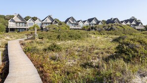 A row of beach houses with a wooden boardwalk leading to them.