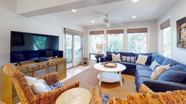 A spacious living room with a flat-screen TV, a sofa set, and a coffee table.