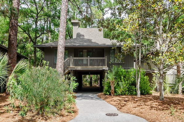 A two-story house with a covered porch and a pathway leading to the entrance.