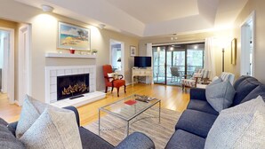 Un salón amplio con chimenea, un sofá grande, una mesa de centro y un televisor.