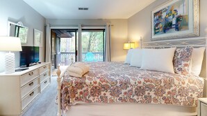 Un dormitorio con una cama grande, televisor, cómoda y un cuadro en la pared.