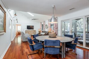 A modern dining area with a round table, blue chairs, and a pendant light.