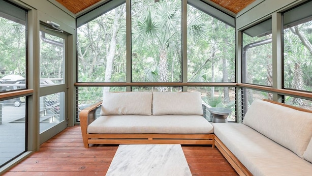 Ein modernes Interieur mit Holzbalkendecke, großen Fenstern und einer hölzernen Bank.