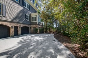 A two-story residential building with a brick facade, a driveway, and a tree-lined path.
