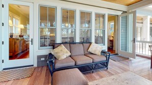 Un salón acogedor con un sofá modular, ventanas amplias y techo de madera.