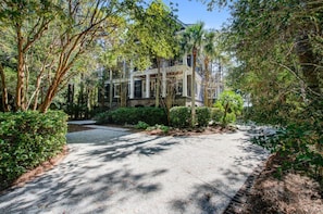 A two-story house with a covered porch and a driveway leading to the entrance.
