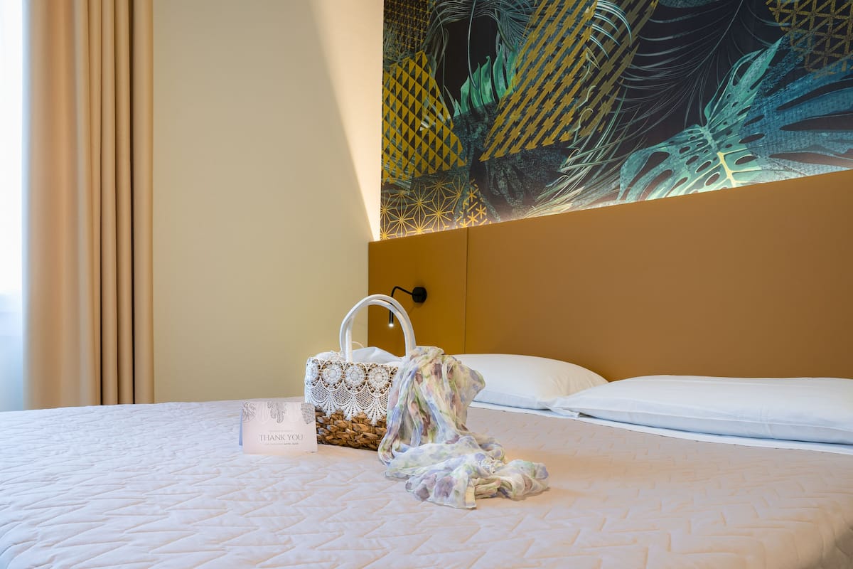 A neatly made bed with a quilted pattern, a white pillow, and a decorative wall hanging above it.