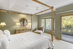 Relax in a serene bedroom with a large bed, wooden four-poster frame, and a comfortable chair.