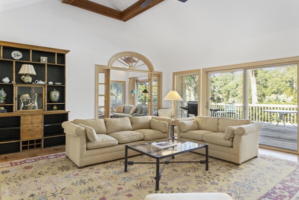 Relax in this inviting living area with a comfortable sofa, wooden shelving, and a large arched mirror.