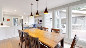 A spacious kitchen with a large wooden island, pendant lighting, and a view to the outdoor deck.