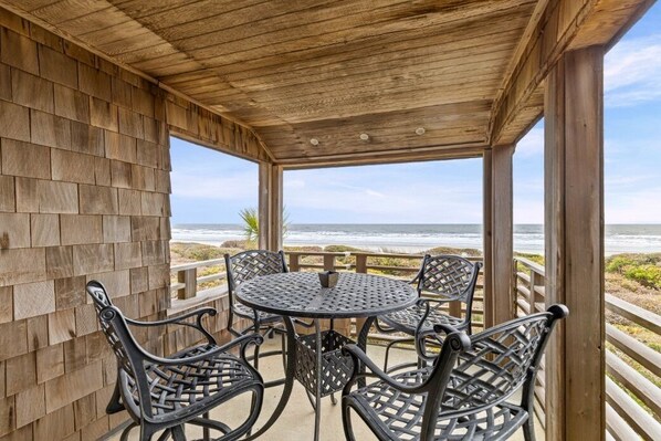A covered outdoor seating area with a view of the ocean.